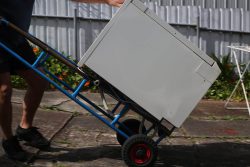 Person moving a washing machine on a trolley